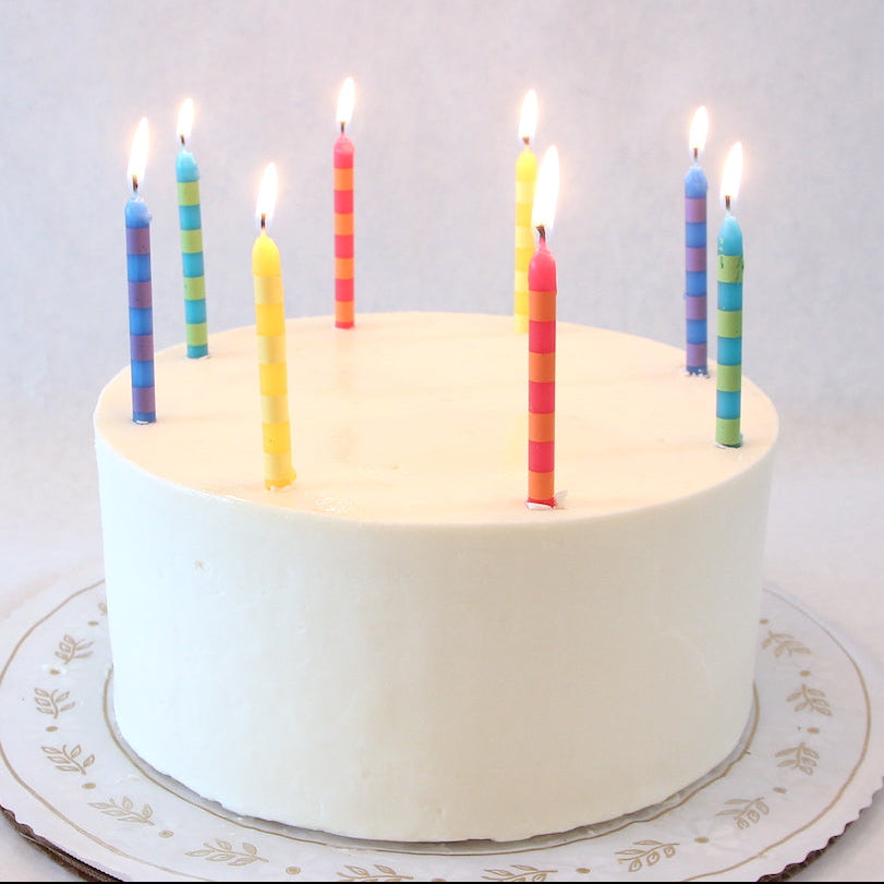 White cake with lit candles on a white background