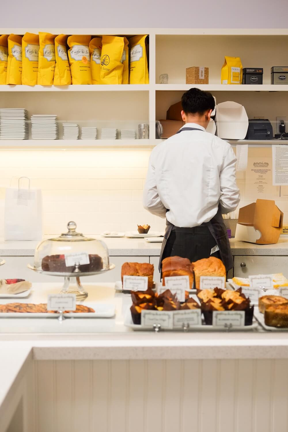 A team member preparing orders behind the pastry counter at Lilac Pâtisserie in Santa Barbara.