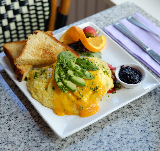 A cheese and avocado omelette served with gluten-free toast and fresh fruit at Lilac Pâtisserie, a breakfast café in Santa Barbara.