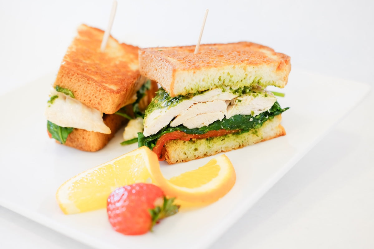 A grilled chicken sandwich on toasted gluten-free bread with pesto and spinach, served at Lilac Pâtisserie in Santa Barbara.