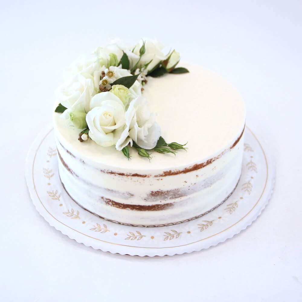 A beautifully decorated sweetheart cake with naked vanilla frosting and fresh white flowers, perfect for weddings and celebrations at Lilac Pâtisserie in Santa Barbara.